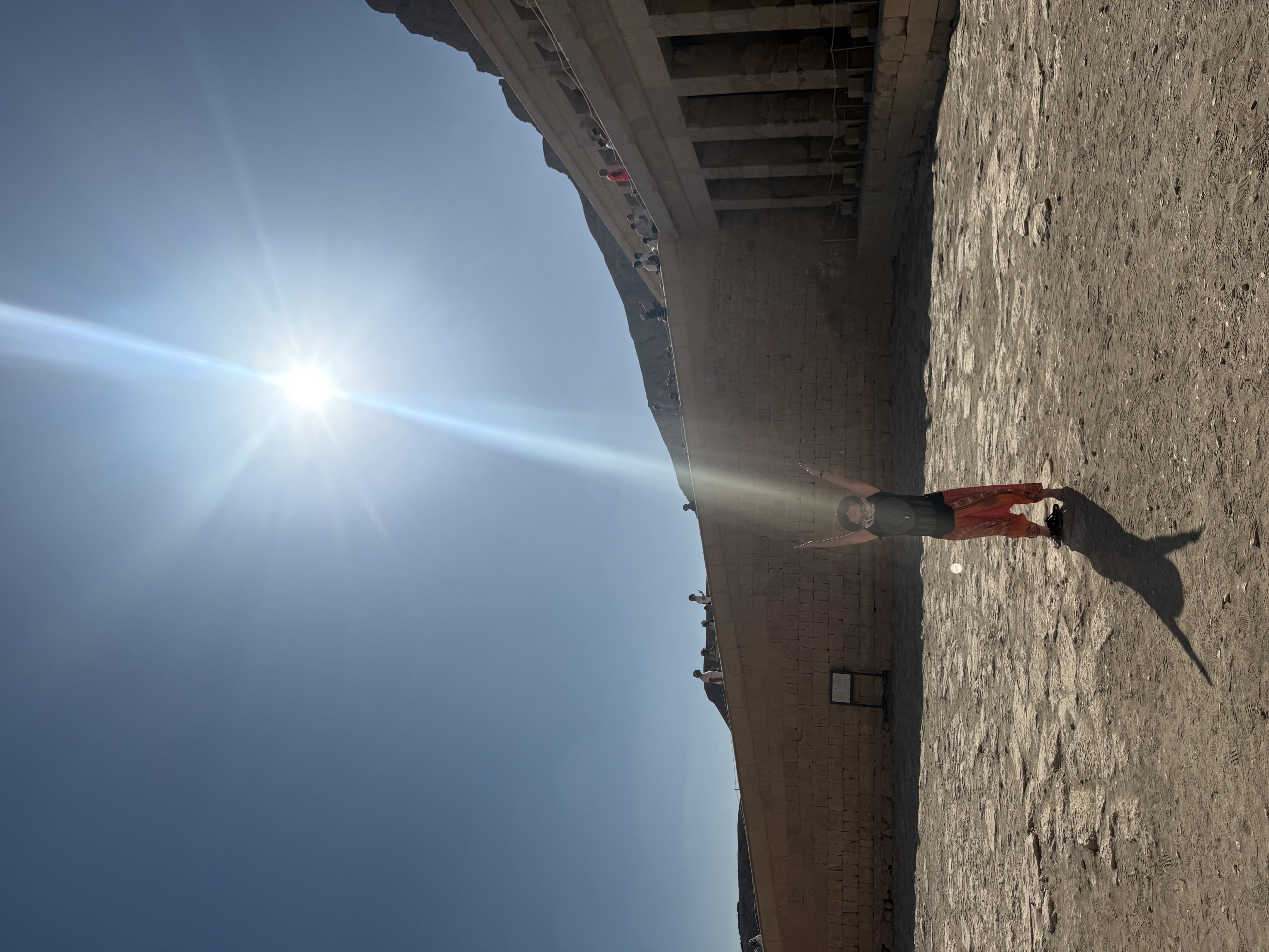 A woman standing beneath a bright beam of sunlight at an Egyptian temple