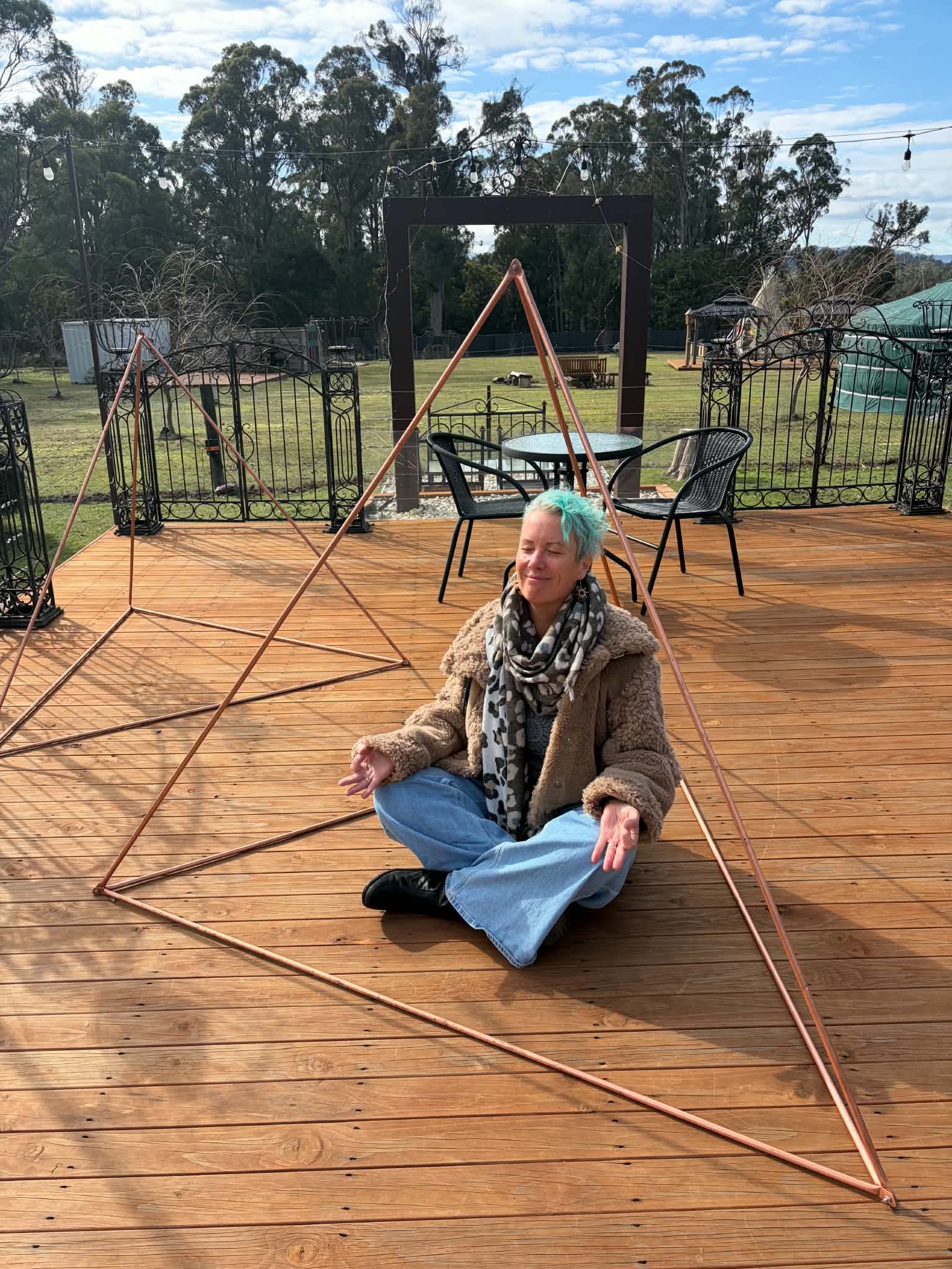 Mel sitting joyfully within copper meditation pyramids