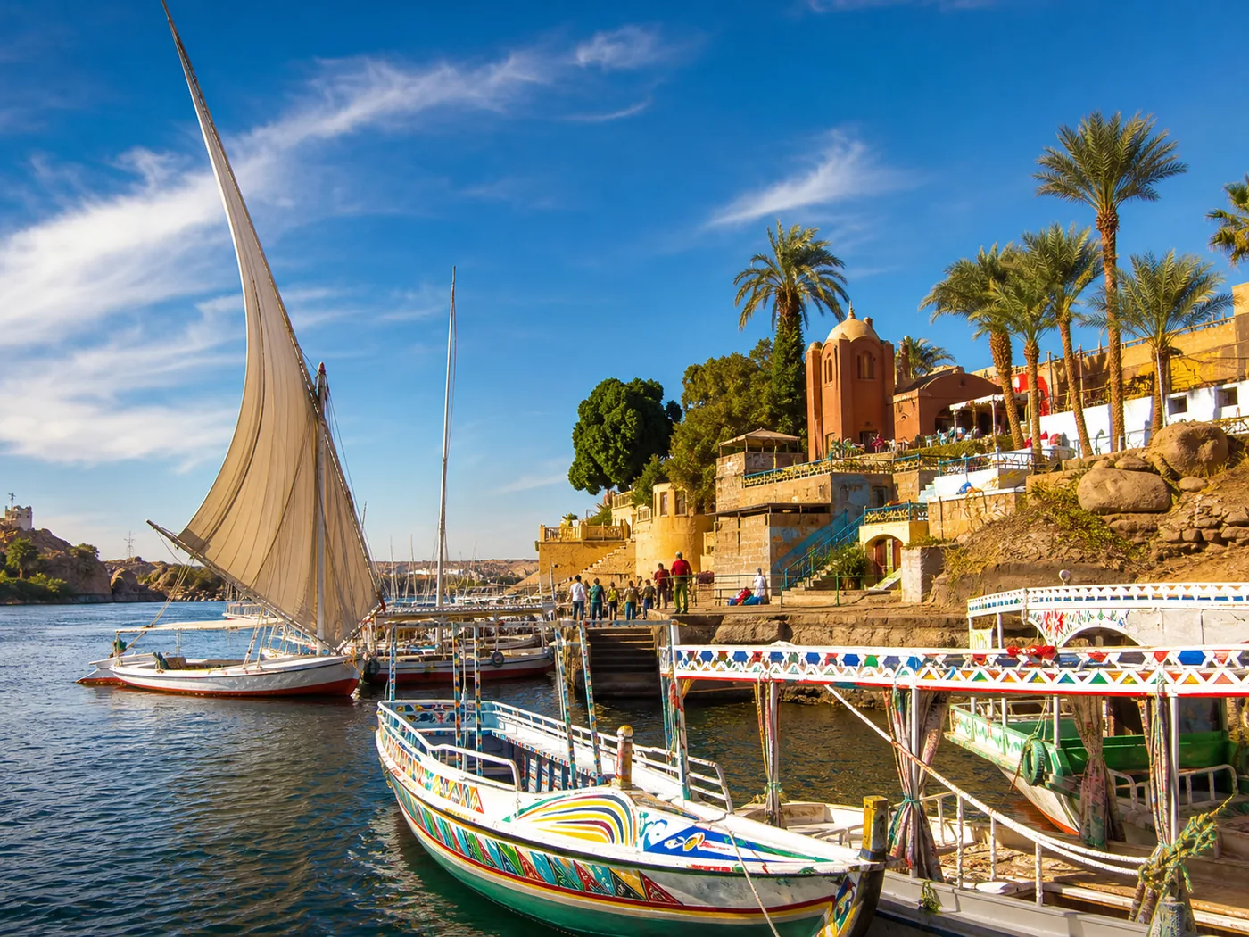 Colourful boats and a felucca on the Nile beside the Aswan waterfront